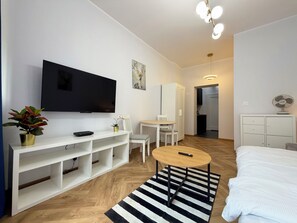 Ein modernes Hotelzimmer mit Flachbildfernseher, Essbereich, Bett und kleinem Tisch.