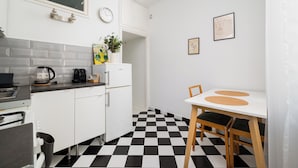 A kitchen with a checkered floor, white cabinets, a coffee machine, and a dining table with chairs. - 3 Maja Cozy Apartment (Warszawa)