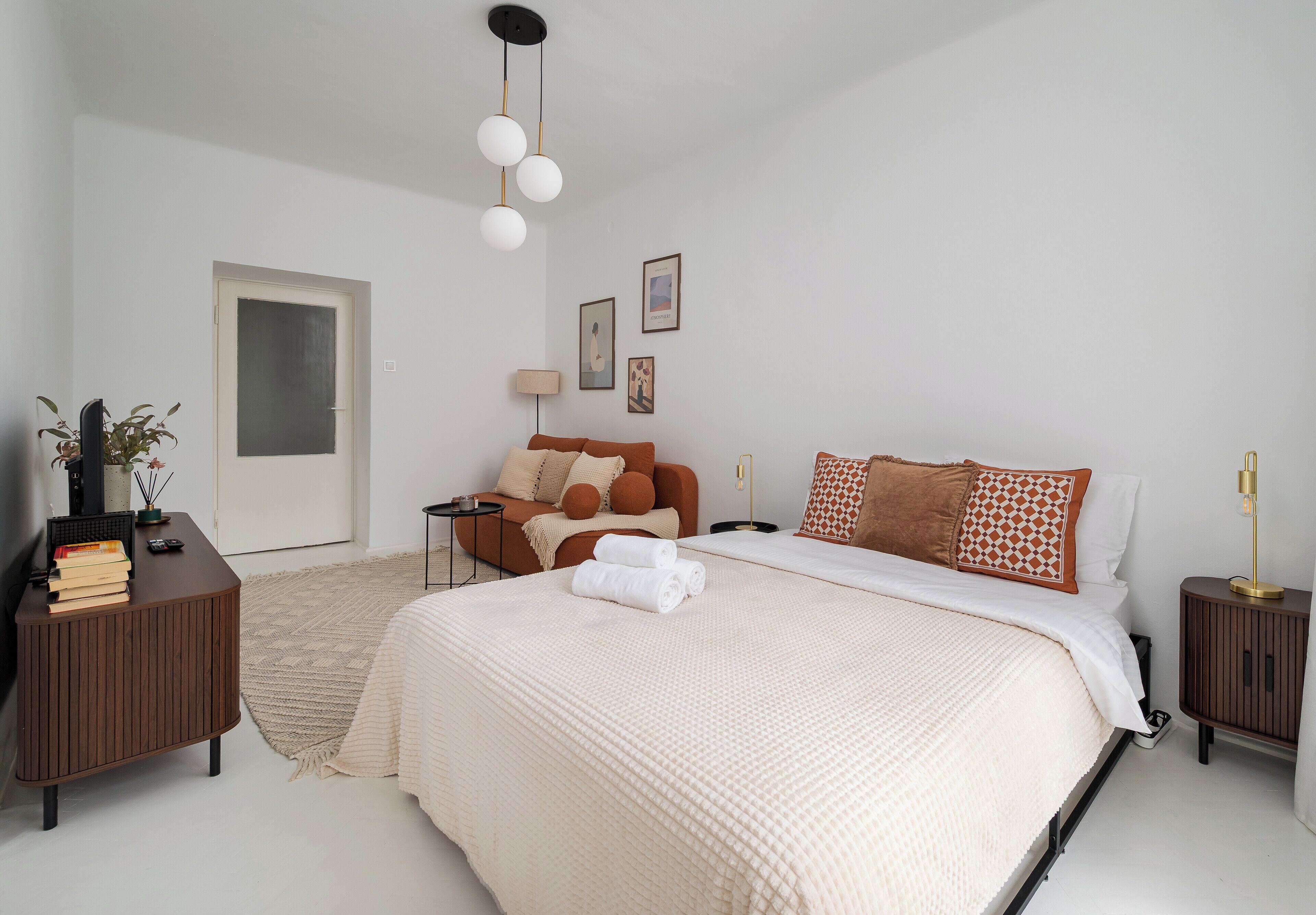Ein Schlafzimmer mit einem großen Bett, Nachttischen, einem Schminktisch, einer Tür und Wandbildern.