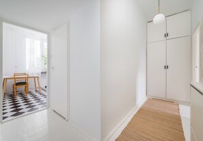 Una habitación con suelo a cuadros, una silla de madera, una puerta blanca y un armario con tiradores negros.