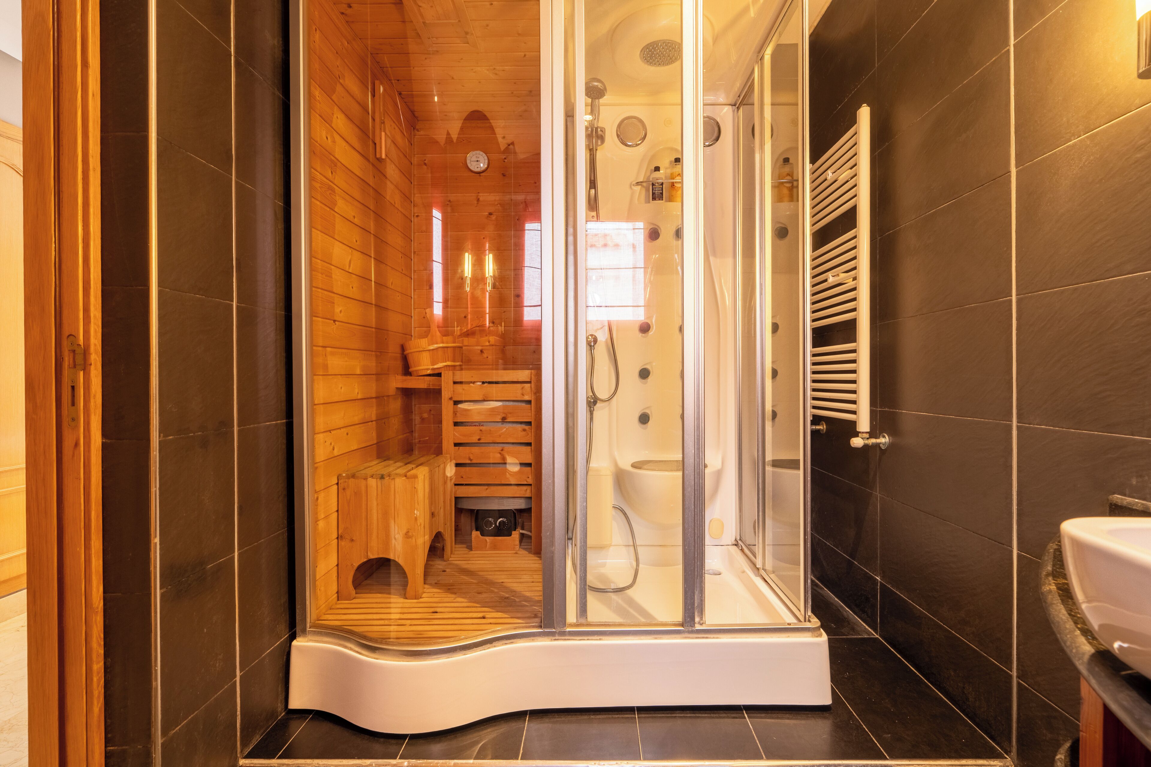Un baño moderno con ducha de vidrio, detalles de madera y un lavamanos blanco.