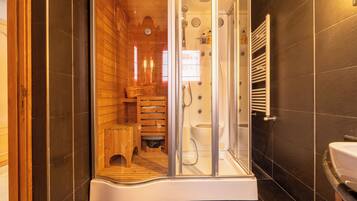 Un baño moderno con ducha de vidrio, detalles de madera y un lavamanos blanco.