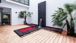 A modern outdoor area with a wooden deck, a black vertical water feature, and a small waterfall. - Exceptional Villa with Pool, Jacuzzi, and Sauna—2 Minutes from the Beach (Dar Bouazza)