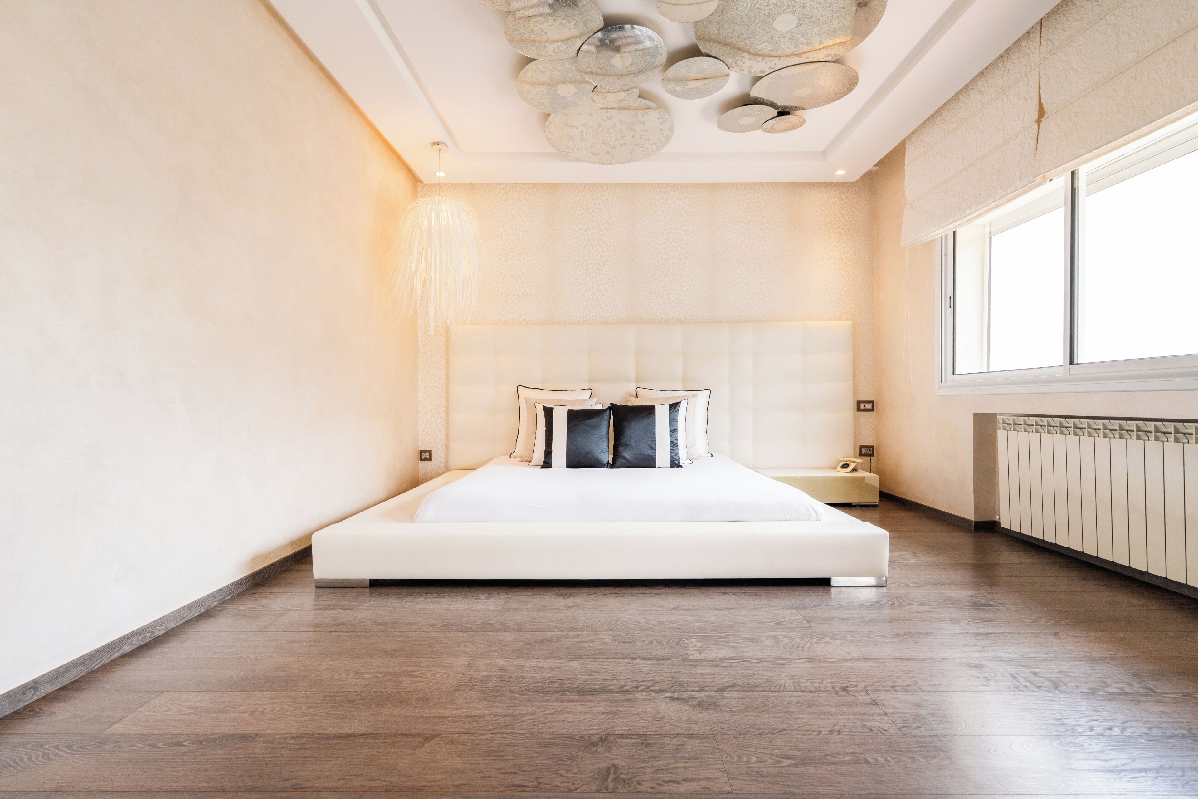 Une chambre à coucher moderne avec un grand lit, une table de chevet et une fenêtre.