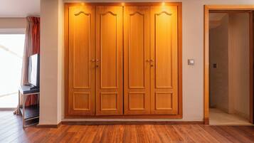 Una habitación con un armario de madera, televisor y una puerta que da a otra estancia.