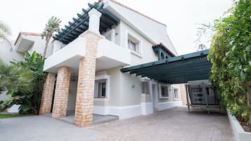 A two-story house with a covered patio area, stone pillars, and a tiled entrance.