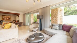 A modern living room with a white sofa, a round coffee table, and a stone wall. - Exceptional Villa with Pool, Jacuzzi, and Sauna—2 Minutes from the Beach (Dar Bouazza)