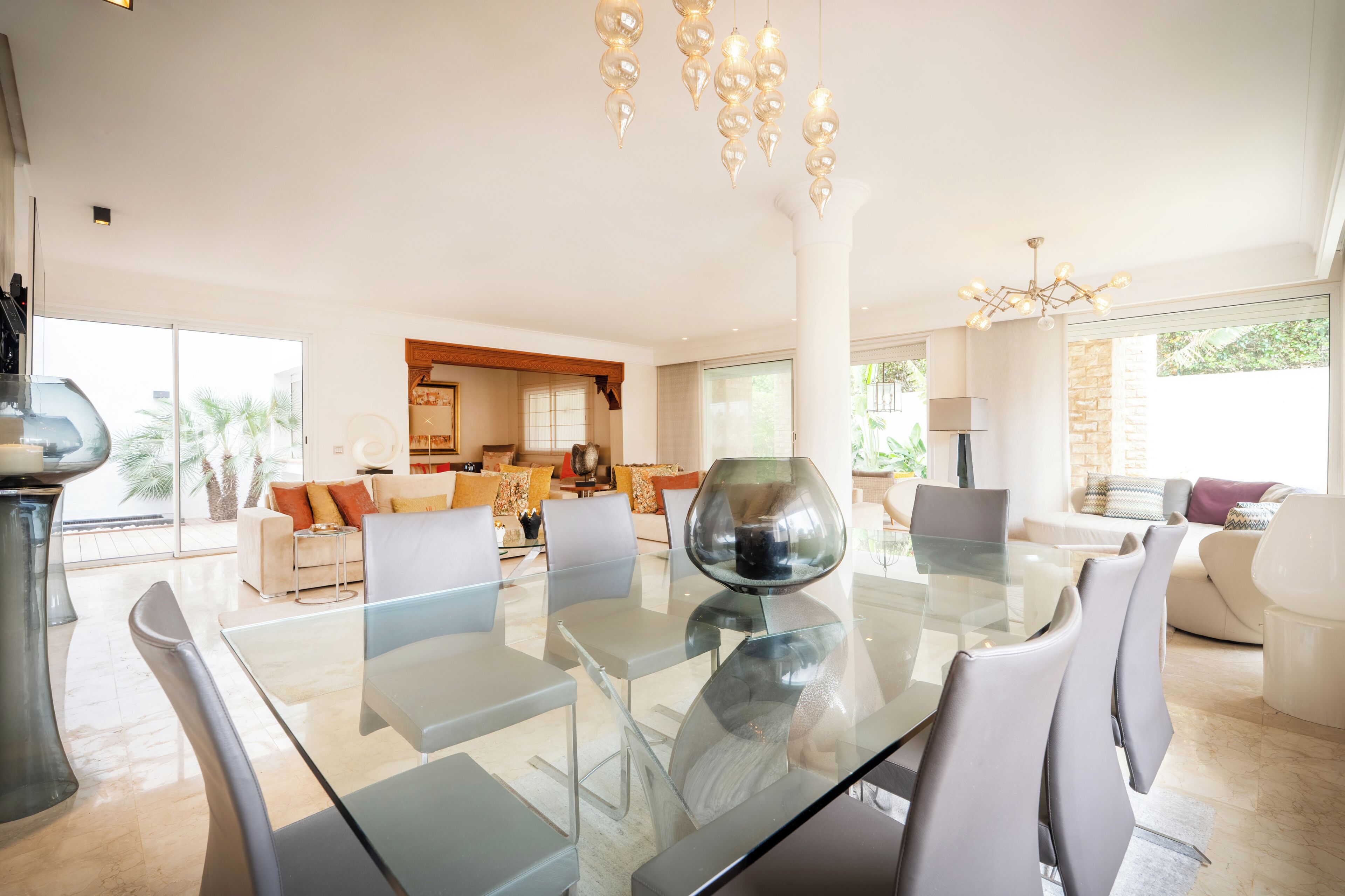 Ein modernes Wohnzimmer mit einem Glastisch, bequemen Sitzgelegenheiten und einer Chandelier.