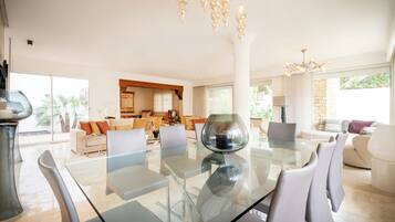 Ein modernes Wohnzimmer mit einem Glastisch, bequemen Sitzgelegenheiten und einer Chandelier.