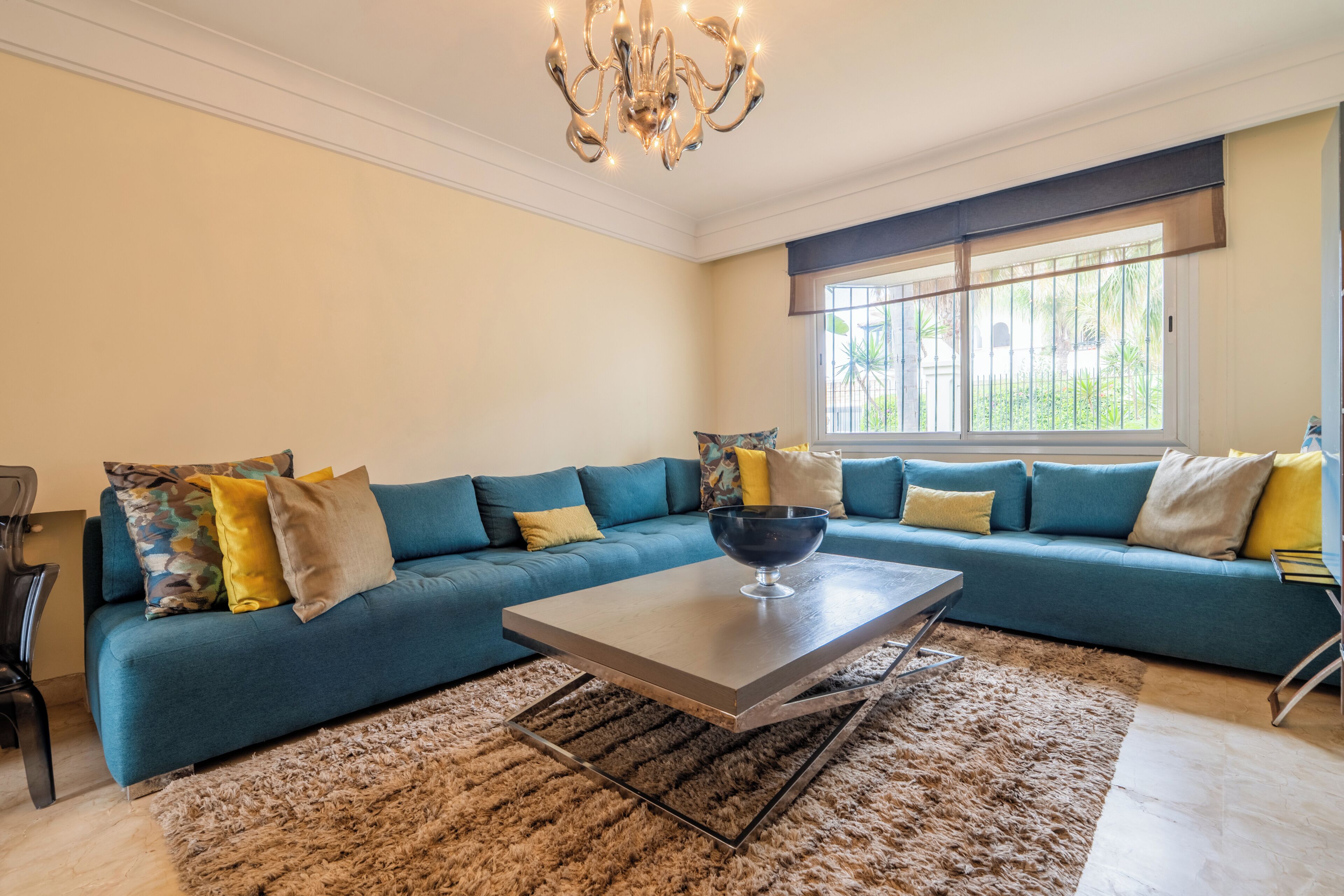 Una sala de estar moderna con un sofá modular, una mesa de centro y una araña.