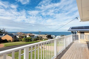 A residential area with a view of the sea, a wooden deck, and solar panels on rooftops. - Mollymere | Ocean View Coastal Retreat (Mollymook Beach)