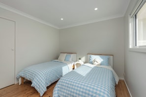 A bedroom with two beds, a window, and a door. - Mollymere | Ocean View Coastal Retreat (Mollymook Beach)