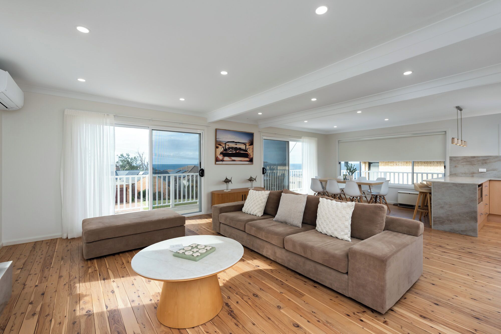A spacious living area with a sofa, a round coffee table, and a dining area with a table and chairs.