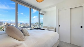 Moderni hotellihuone, jossa on suuri sänky, tuoli ja vaatekaappi.