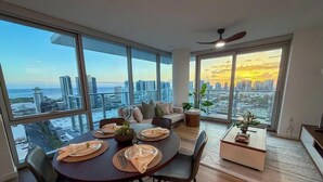 Un soggiorno moderno con zona pranzo, ampie finestre vista città e ventilatore a soffitto.