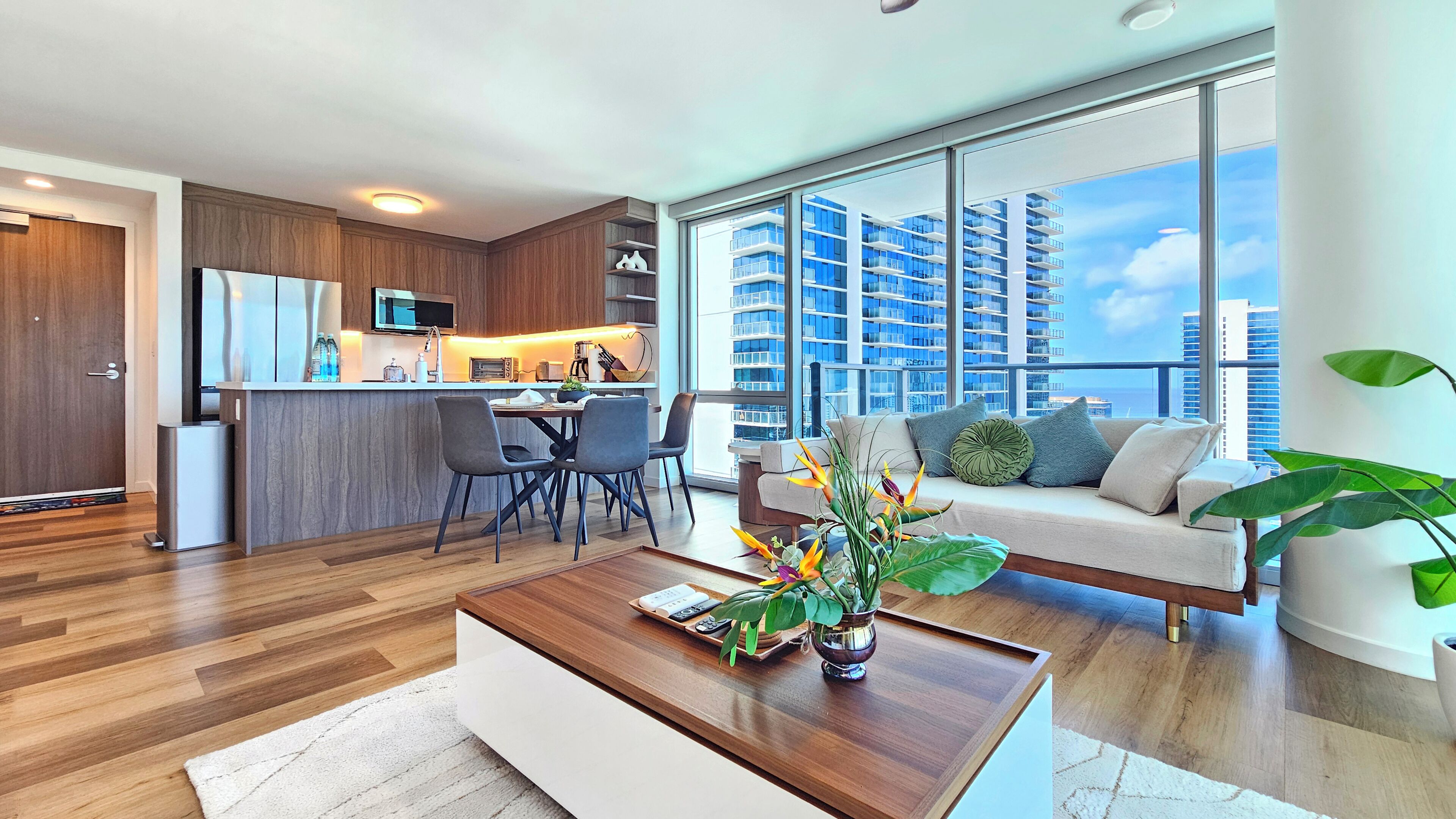 Un appartement moderne comprenant un coin repas, une cuisine et un grand balcon offrant une vue sur la ville.