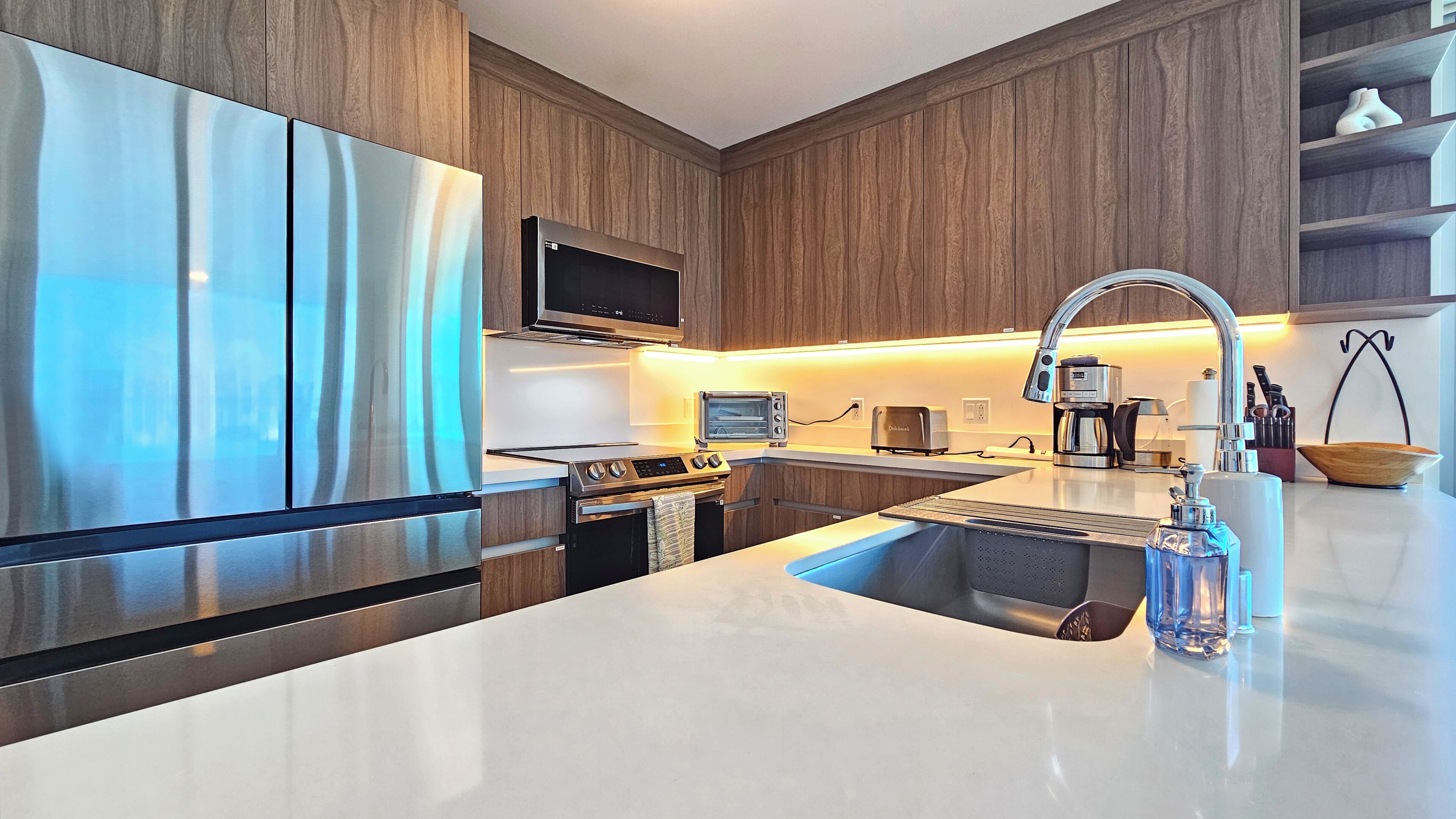 A modern kitchen with stainless steel appliances, a built-in oven, a microwave, a toaster, and a coffee maker.