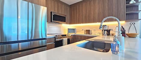 A modern kitchen with stainless steel appliances, a built-in oven, a microwave, a toaster, and a coffee maker.