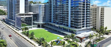 A modern high-rise building with multiple floors, a central courtyard, and a playground.