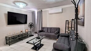 A living room with a flat-screen TV, a sofa, a coffee table, and a floor lamp.