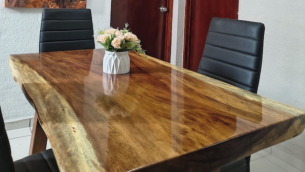 A conference room with a wooden table, two black chairs, a white vase with flowers, and a painting on the wall.