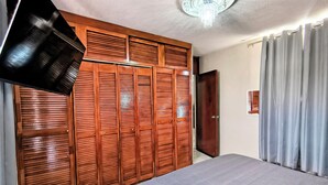 A bedroom with a bed, wooden wardrobe, and a ceiling light fixture.