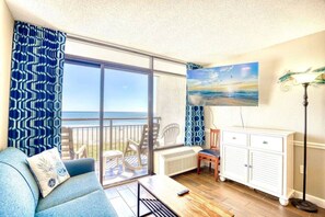 Ein Balkon mit Blick auf das Meer, eine Couch mit Kissen, ein Tisch, eine Heizung und ein Schrank.