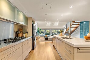 A modern kitchen with a central island, built-in appliances, and a view to the living area. - Spacious Waterfront Loft at Woolloomooloo Wharf (Woolloomooloo)
