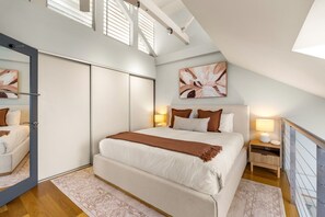 Une chambre à coucher avec un grand lit, une armoire, une table de chevet avec une lampe et un tableau au mur.