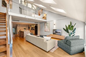 Eine moderne Loft-Wohnung mit Zwischengeschoss, offener Wohnbereich, Küche und einem großen Fenster für natürliches Licht.