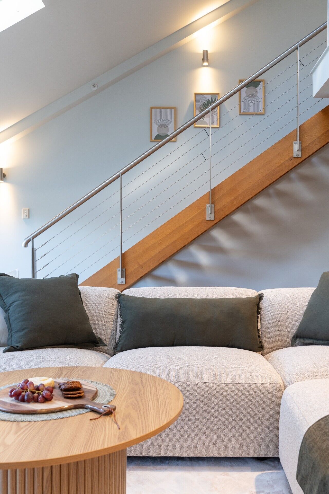 Ein modernes Wohnzimmer mit einer Holztreppe, einer Sofagarnitur und einem Couchtisch mit Snacks.