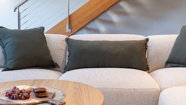 A modern living room with a wooden staircase, a sofa set, and a coffee table with snacks. - Spacious Waterfront Loft at Woolloomooloo Wharf (Woolloomooloo)