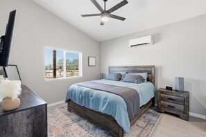A bedroom with a bed, a nightstand, a TV, a ceiling fan, and a window. - Quite 1-bedroom house with mountain views in Oro Valley. (Oro Valley)