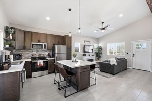 A modern kitchen with a central island, bar stools, a built-in oven, microwave, and refrigerator. - Quite 1-bedroom house with mountain views in Oro Valley. (Oro Valley)