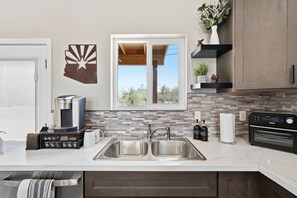 A modern kitchen with a double sink, a coffee maker, a toaster, and a built-in oven. - Quite 1-bedroom house with mountain views in Oro Valley. (Oro Valley)