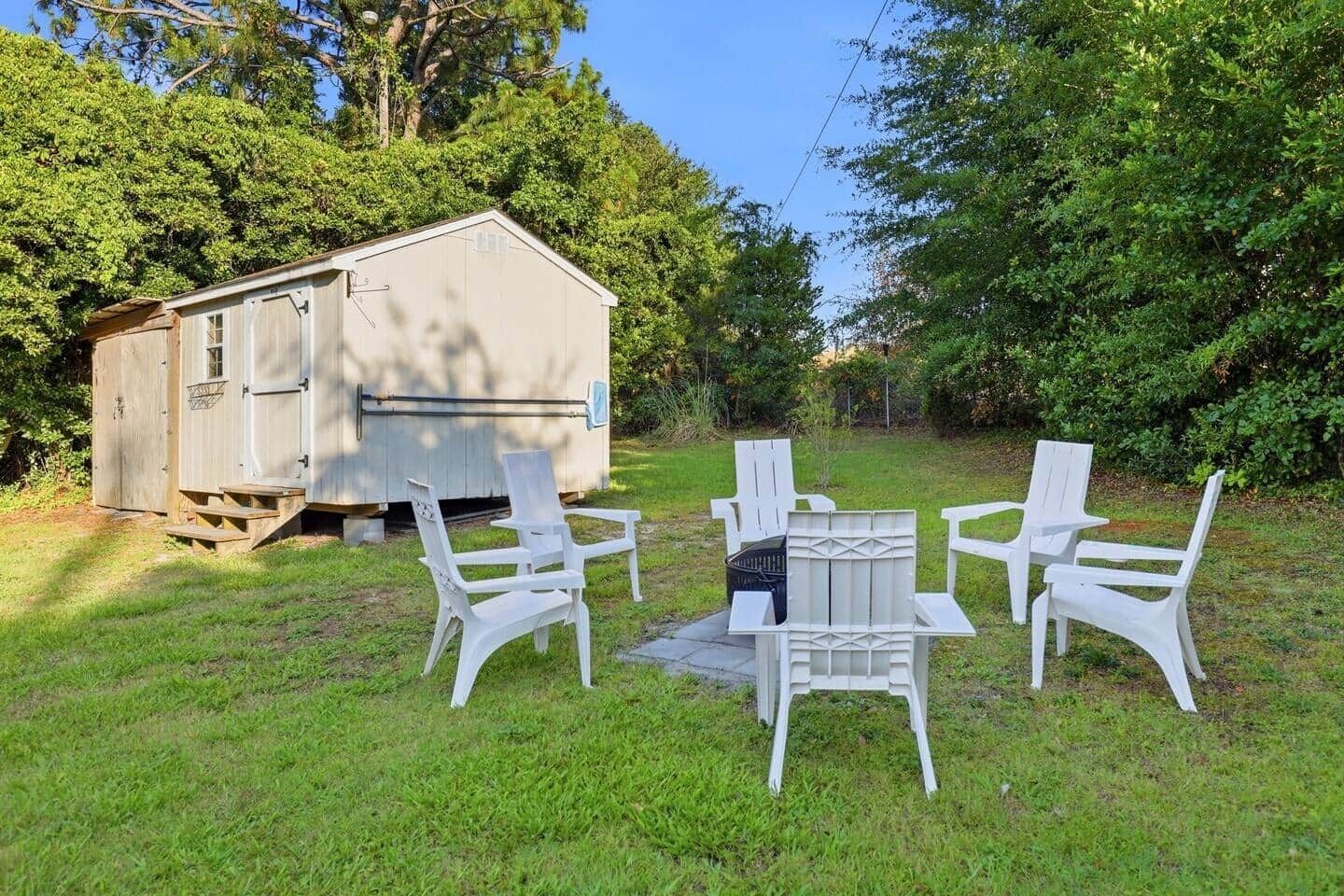 A small wooden shed with a bench and chairs in front.