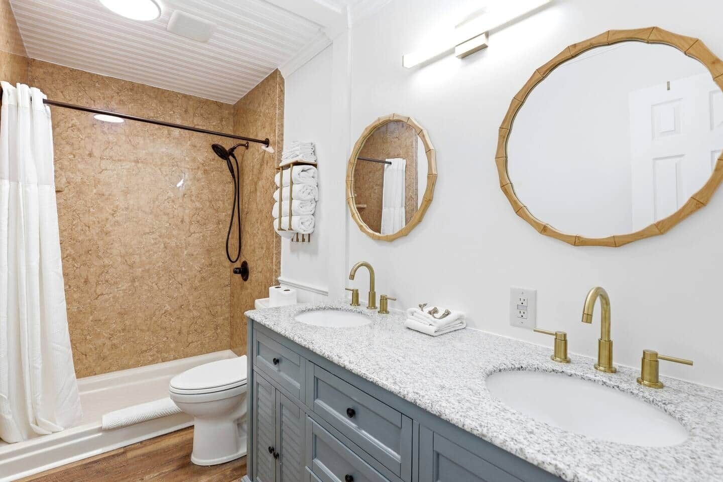 A bathroom with two sinks, a shower, and two mirrors.