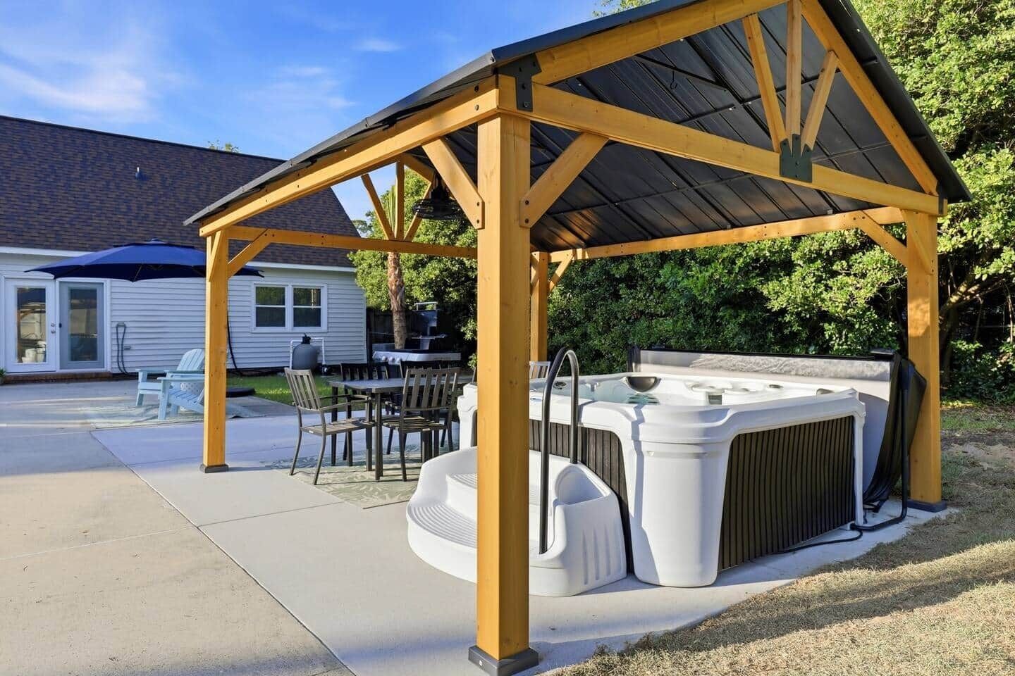 A covered outdoor area with a hot tub and seating.
