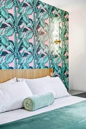 Un dormitorio con cama, almohadas y cabecera.