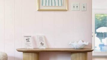 A room with a wooden table, a framed artwork, and a small white basket.