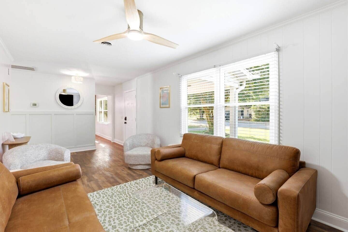 A living room with a brown leather sofa, a round armchair, and a patterned rug.