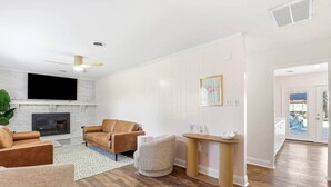 Ein Wohnzimmer mit Kamin, Ledersofa und Fernseher.