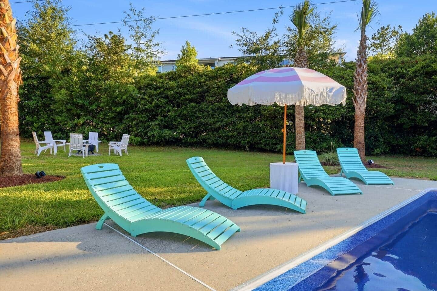 Un espace aménagé au bord de la piscine, avec des chaises longues, une table et un parasol.