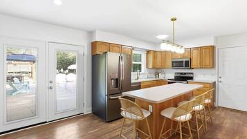A modern kitchen with a central island, stainless steel appliances, and wooden cabinetry.