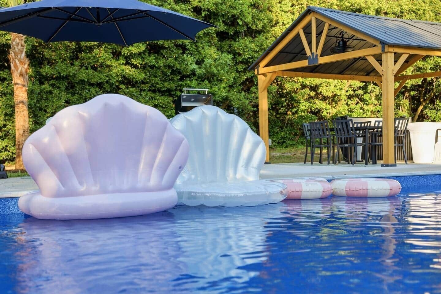 Una piscina con flotadores inflables y un área de estar cubierta.