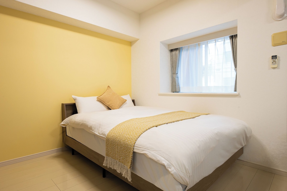 Un dormitorio con cama, una ventana con cortinas y un termostato en la pared.
