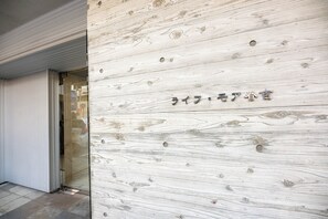 Un mur en bois avec une zone en retrait, qui pourrait servir d’espace d’accueil ou de salle d’attente, et une porte en verre donnant sur un espace intérieur.