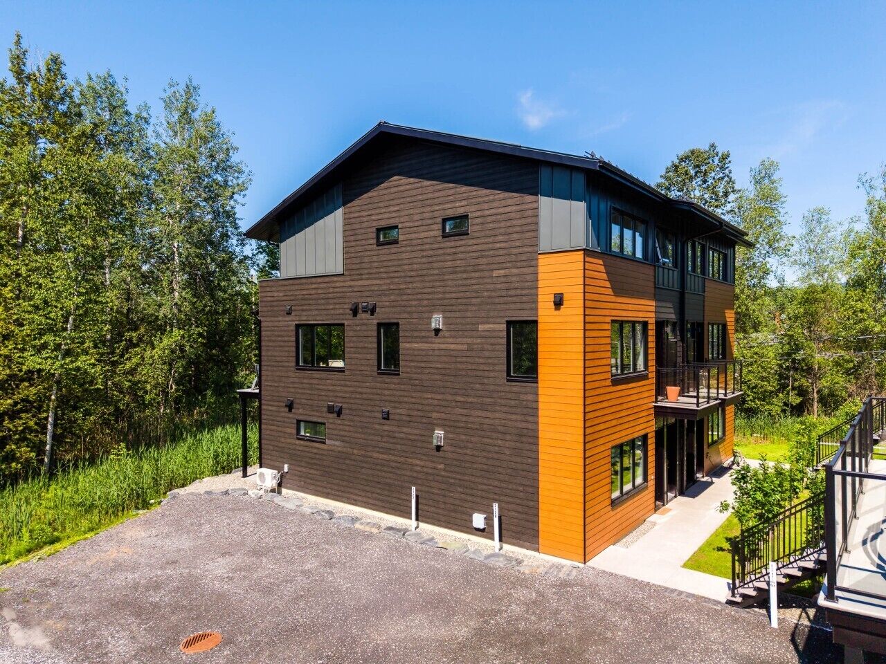 A modern two-story building with a flat roof, large windows, and a mix of brown and orange exterior panels.