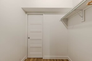 Una puerta blanca de diseño sencillo, suelo de madera y un accesorio metálico en la pared.