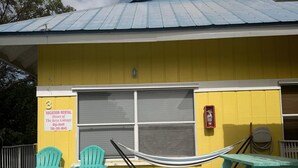 A yellow building with a covered deck, two turquoise Adirondack chairs, a hammock, and a picnic table. - Heart of the Key Cottage (Marathon)